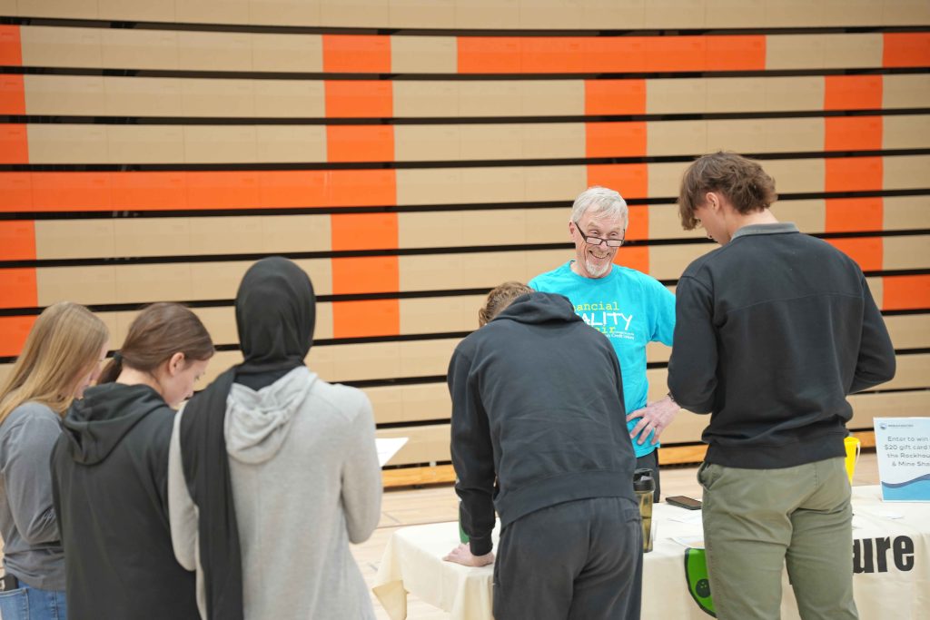 Photo of volunteer at the Financial Reality Fair, which reads "Join our volunteer network."