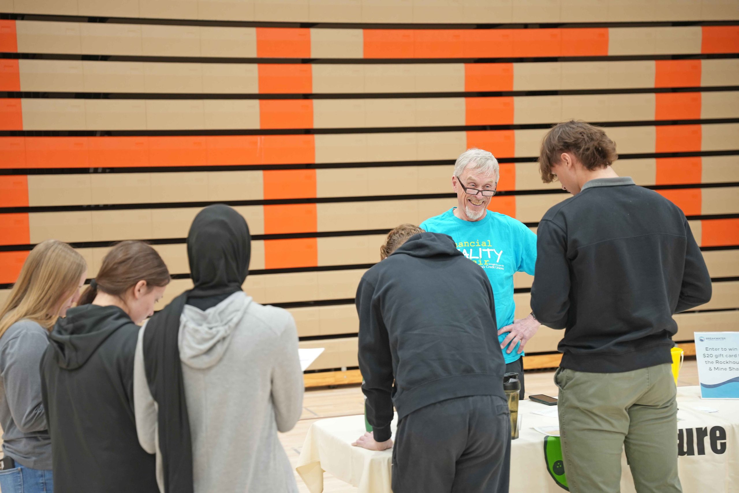 Photo of volunteer at the Financial Reality Fair, which reads "Join our volunteer network."