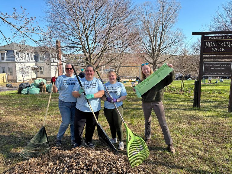 Employees pose for a picture at Pitch in for Parks, holding rakes and compost bags.