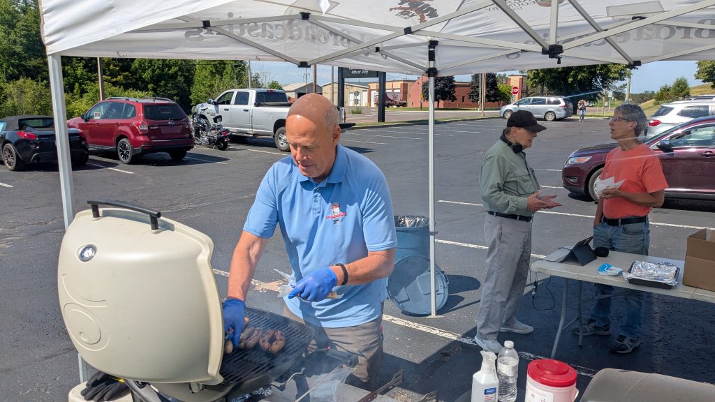 Jay from J&J Broadcasting puts brats on grill for member cookout.