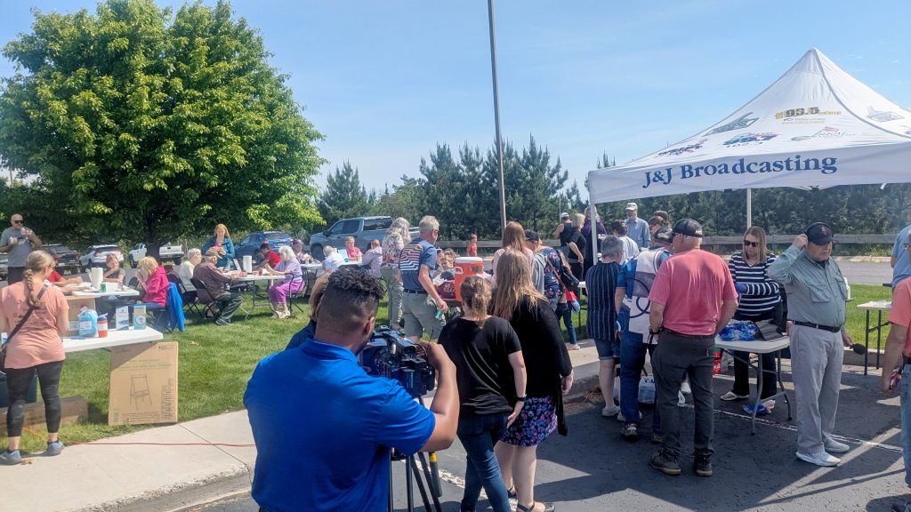 Large crowd gathers for member cookout. Reporter can be seen recording for TV6.