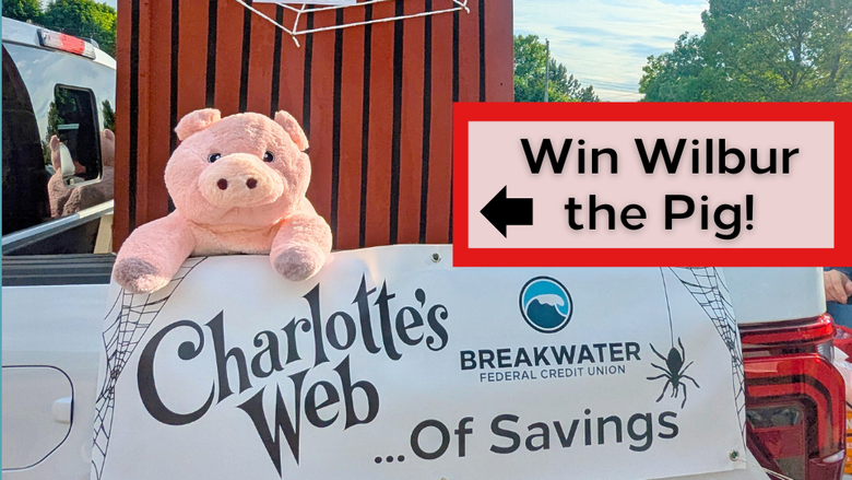 Photo of parade float. Banner says "Charlotte's Web of Savings" with Breakwater logo. Wilbur the pig is hanging over the side of the truck, with a large barn shaped structure covered in spider web behind him. Text on photo says "Win Wilbur the Pig!" with an arrow pointing towards the stuffed pig.