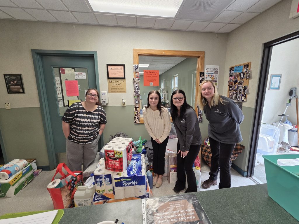 Staff member from CCHS and three from Breakwater pose with large pile of supplies donated to CCHS.
