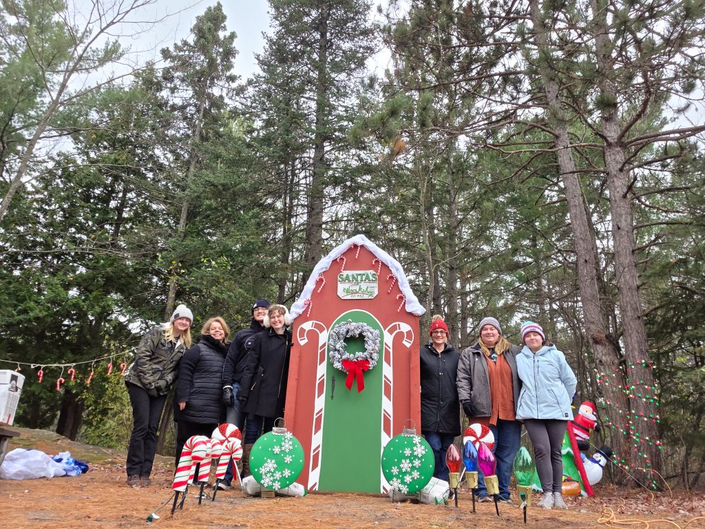Breakwater employees pose for photo next to Santas Workshop designed for Hancock Lights the Night event.