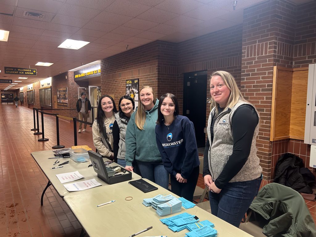 Breakwater employees pause for a photo while volunteering at the Pigs-n-Heat hockey game fundraiser.