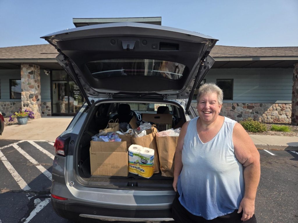 Darlene Eakin from St. Vincent de Paul pauses for a photo with a trunk full of donated food items and everyday essentials for the food bank.